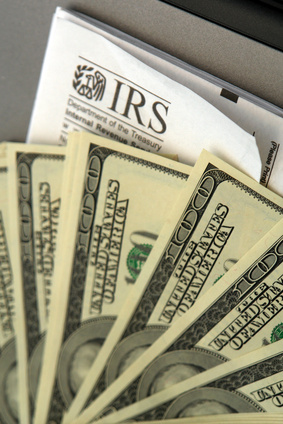 Stack of hundred dollar bills laid out on top of IRS form,